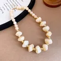 Close-up of elegant cream acrylic beaded necklace with gold accents on a tan background - 68# Necklace / Khaki