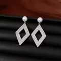 Detalle macro de pendientes plateados con forma de rombo, circonitas y perlas finas - Estilo de Rombo Hueco / Plata-Blanco