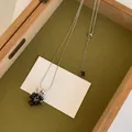 Vue détaillée d'un collier pendentif grappe de raisin sur un plateau en bois minimaliste. - Collier (HN12813) / Argent-Noir