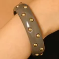 Vintage grey resin bangle featuring decorative gold studs worn on a model's wrist accessory - Rivet Style / Gray