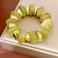 Detailopname van groene marmeren acrylkralen en goudkleurige kralen op een elastische armband. - Groen