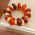 Macro-weergave van een luxe elastische armband met amberen acryl en gouden kralen. - Bruin