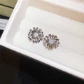 Primer plano detallado de pendientes de flores bañados en oro de 18k con circón central - Estilo de Pasador de Plata / Plateado