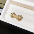Primer plano de elegantes pendientes de flor bañados en oro con circones brillantes - Estilo de Pasador de Plata / Dorado