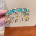 Vista dettagliata del bracciale rigido dorato con perle crackle blu e ciondoli pendenti. - Bracciale-Oro-Blu