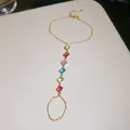 Zoom sur le bracelet bague en zircons multicolores avec chaîne dorée élégante et chic. - Carré Coloré / Or