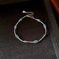 Detailed view of silver chain bracelet featuring blue mesh oval beads in a jewelry box. - Bracelet-Blue
