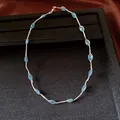 Detailed view of minimalist necklace with blue beads and silver mesh on black display. - Necklace - Silver - Blue