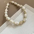 Detail view of a chunky acrylic marbled bead necklace with gold-toned spacers and chain - Khaki