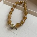 Detailed view of amber twisted acrylic beads on an adjustable gold-tone choker. - Light Coffee