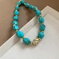 Detail shot of turquoise acrylic twisted beads with golden spacers on a necklace. - Green