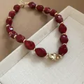 Close-up of red acrylic twisted bead necklace with gold metallic accents and adjustable clasp. - Red