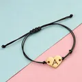 Detail of adjustable black cord bracelet with gold heart charm and cut-out letter A - Letter A / Gold Black Rope