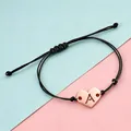 Close-up of rose gold heart charm with hollowed letter A on braided bracelet - Letter A / Rose Gold Black Rope