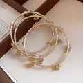 Nahaufnahme von goldenen Armreifen mit Metallperlen-Quasten auf einem Schmucktablett - Gedrehtes Seil Blumenanhänger Armreif Set (37) / Gold