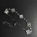Detailed shot of an adjustable silver bracelet featuring zircon stones and pearl clover charms. - Silver