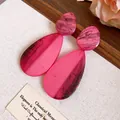 Vue détaillée des boucles d'oreilles en résine rose marbrée en forme de goutte d'eau. - Larme / Rose rouge