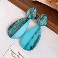 Detailaufnahme von blaugrünen Harzohrringen mit schwarzen Marmormustern - Tropfenform / Blau