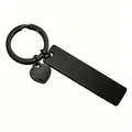 Close-up of a black stainless steel keychain with a rectangular plate and heart charm. - Black