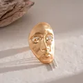 High-detail macro shot of a golden artistic portrait mask pendant with silver chains. - Ring / Gold