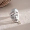 Detail showing the intricate human mask pendant with tassel chain in silver finish. - Ring / Silver