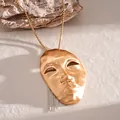 Close-up of an artistic gold human mask pendant featuring a silver chain tassel detail - Necklace / Gold