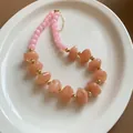 Chunky acrylic beaded necklace with pink and peach stones on a white ceramic plate - Pink