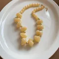 Élégant collier vintage en perles d'acrylique jaune crème avec séparateurs dorés sur assiette - Khaki