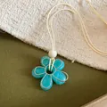 Gros plan d'un pendentif fleur en résine turquoise sur un fond de tissu texturé élégant - Bleu