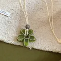 Gros plan détaillé d'un collier pendentif fleur en résine verte sur fond de tissu - Vert