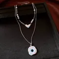 Nahaufnahme einer zweilagigen Halskette mit Perlen, Herzanhänger und Donut-Motiv - Halskette / Silber Weiß Blau