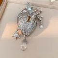 Macro view of a silver rhinestone anatomical heart brooch with keyhole and pearl charms. - Silver Style (HP1030)