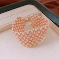 Detailed close-up of a woven glass bead bracelet featuring a gold magnetic clasp. - Bracelet / Gold-White