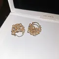 Makroansicht eleganter hohler Blumenkorb-Ohrringe mit Perlen und Kristallen geschmückt - Hohlkorb-Stil / Gold