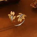 Detailaufnahme des zweifarbigen offenen Blattrings aus Titanstahl mit goldenen Akzenten. - A314 Zweig Ring
