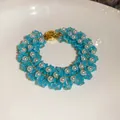 Detailed macro shot of a hand-woven bracelet with blue glass beads and white pearls. - Style 80 Bracelet / Gold-Blue