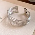 Vue détaillée d'un bracelet manchette ouvert argenté à plusieurs couches sur fond texturé - Style 58 / Argent