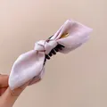 Detailed view of the pink satin bow hair claw clip with a elegant gold metal tag - Twist Clip / Pink