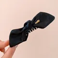 Close-up of black fabric bow hair claw clip with golden classic metal tag detail - Twist Clip / Black