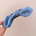 Detailed view of the blue satin bow hair claw clip with a decorative gold metal tag - Twist Clip / Blue