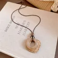 Détail d'un collier avec pendentif carré en résine et tissé bohème sur cordon marron. - Café - Style rond