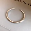 Detailopname van een minimalistische zilver gepolijste metalen open manchetarmband - Glad Rond / Zilver