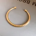 Gedetailleerde macro-opname van een gouden getextureerde open armband met bollen - Gefacetteerde Ronde / Goud