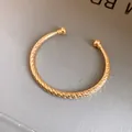 Gedetailleerde macro-opname van een goudkleurige open armband met diamantgeslepen textuur. - Doorsnedestructuur / Goud