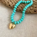Dettaglio di una collana di perle acriliche turchesi venate con pendente a cuore dorato - Collana / Ciano