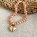 Dettaglio di perle acriliche marmorizzate rosa e pendente cuore in finitura oro - Collana / Rosa