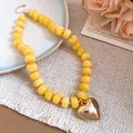 Detail view of a vibrant yellow resin beaded necklace with a gold heart pendant on a linen fabric. - Heart Pendant Beaded Necklace (57#) / Gold + Yellow (57#)