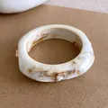 Detailopname van een gemarmerde hars armband versierd met fonkelende strassteentjes - Beige