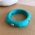 Close-up van een dikke turquoise hars armband met blauwe kristallen accenten - Hemelsblauw