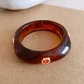 Detailopname van amberkleurige hars armband met oranje kristallen en glinsterende steen - Bruin